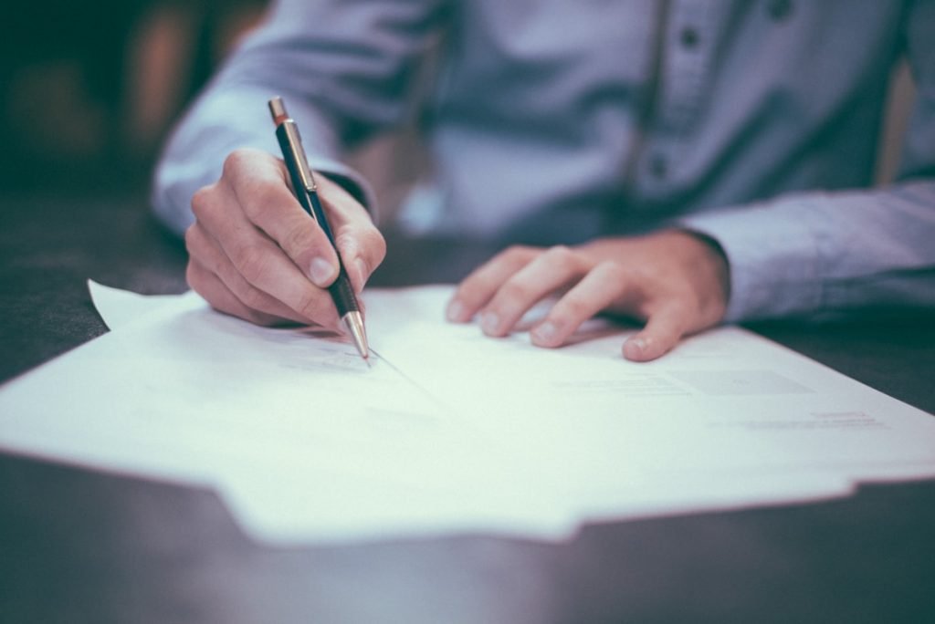Person signing loan documents with a pen